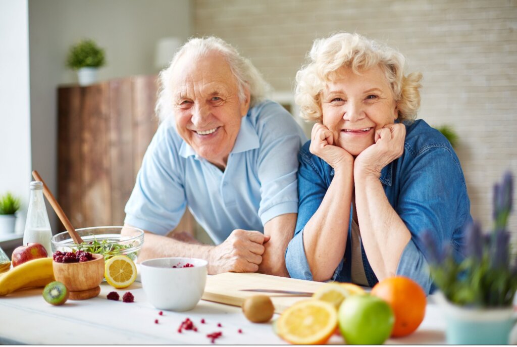 An older couple leaning against a kitchen counter